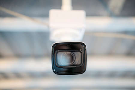 Modern CCTV camera on a wall. A blurred night cityscape background. Concept of surveillance and...