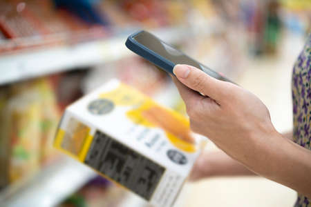 Shopping. Young woman scans the composition of the body cream. Modern technology in everyday life. Close upの写真素材