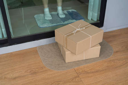 Close-up of a woman receiving parcels delivered to her doorstep. The parcel was placed on the door mat.の写真素材