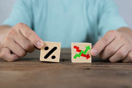 Businessman holds wooden blocks with percent and up or down arrow. Mortgage and loan rates. Interest rate, stocks, ranking. Business and finance concept.の写真素材