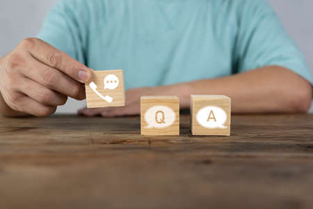 Businessman holding wooden block with question and answer communication icon, breakdown concept. Lack of communication skills.の写真素材