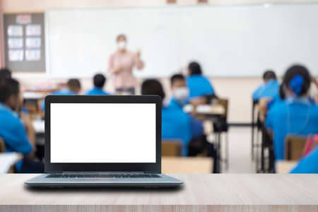 Computer on the table, blur image of the children classroom as background.の写真素材