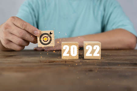 Hand putting wooden cubes 2022 with goal icon on table and white background, copy space. Start new year 2022 with goal plan, goal concept, action plan, strategy, new year business vision.の写真素材