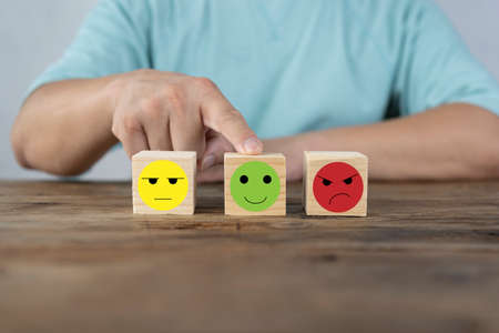 Hand choosing happy smile face wooden block, good feedback rating and positive customer review, mental health assessment, child wellness,world mental health day,think positive, emotional scale conceptの写真素材