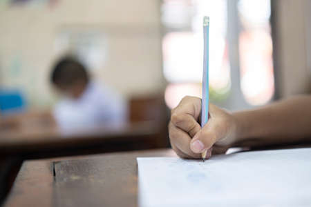 small school boy writing homework from school in workbook, focus hand holding pencilの写真素材