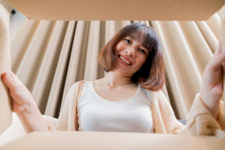 Smiling cute girl opened the box and looked inside. Purchased new and unboxed.の写真素材