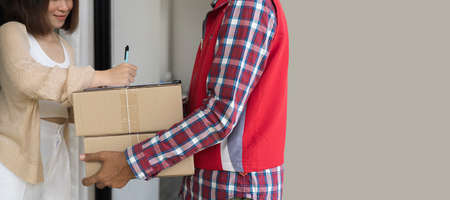 Woman signing receipt of delivery package, close up. Detailed view of a customer signing delivery noteの写真素材