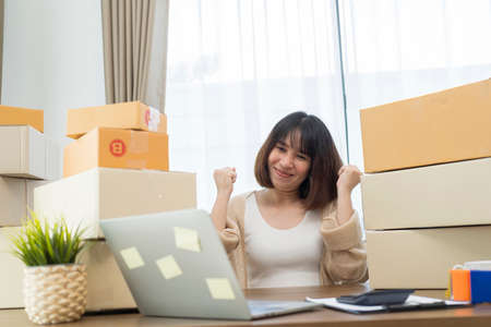 Young Women happy after new order from customer, business owner working at home office packaging on background. online shopping SME entrepreneur or freelance working concept.の写真素材