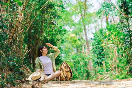 A beautiful and lovely woman traveling the nature of the jungle in Thailand is sitting happily relaxing in a warm atmosphere.の写真素材