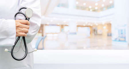 Blurred abstract beautiful luxury hospital and clinic interior. Portrait of a doctor holding a stethoscope greets him at a desk in a modern clinic.の写真素材