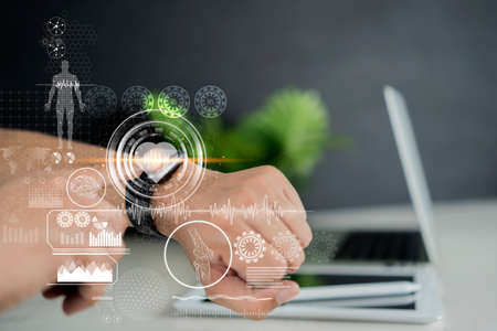Businessman checking her smart watch to realize the status of data protection and personal confidential information. Blue glowing icons. Padlock and business symbols. Concept of cyber securityの写真素材