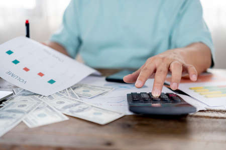 savings, finances, economy and home concept. Close up of man with calculator counting money and making notes at homeの写真素材