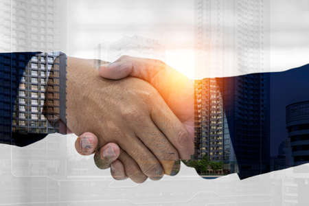 Close up of handshake on abstract city background. Teamwork concept. Double exposure. Filtered imageの写真素材
