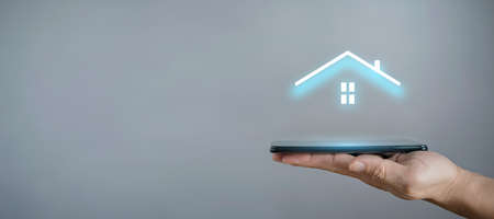 Businessman hold house icon.Smart home controlled, intelligent house, and home automation app concept.Pcb design and person with smart phone. Innovation technology internet Network Conceptの写真素材