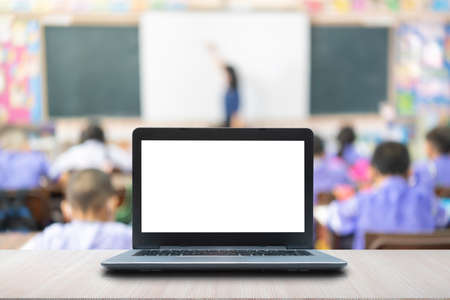 Computer laptop on the table, blur image of the children classroom as background.の写真素材