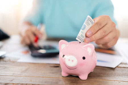 Man hand putting money bank note dollar into piggy for saving money wealth and financial concept.の写真素材