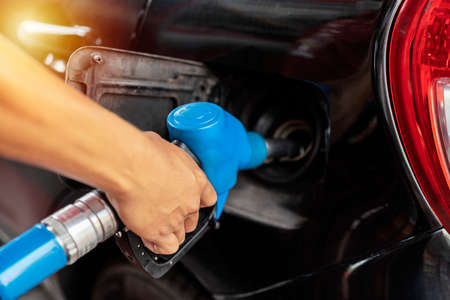 Refueling the car at a gas station fuel pump. Man driver hand refilling and pumping gasoline oil the...