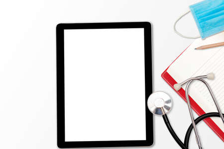 Stethoscope on medical table Healthcare and technology concept, tablet pc, stethoscope, medical mask, notebook and pencil.の写真素材