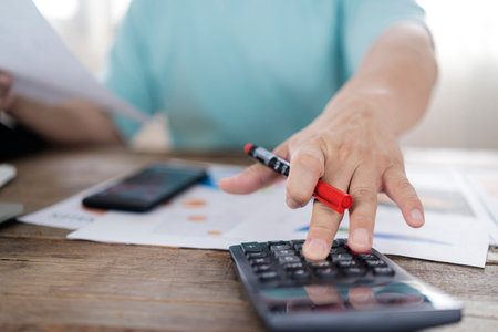 Close up hand of stress young asian businessman,male is pressing a calculator to calculate tax...