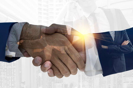 close up. business people shaking hands with each other. Businessmen shaking hands on abstract city and forex chart background. Teamwork concept. Double exposureの写真素材