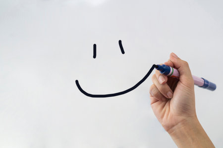 Hand writing with a black mark on a transparent board - Smileyの写真素材