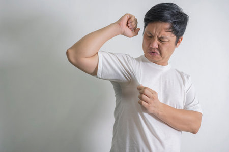 Adult guy held his nose with his hands while feeling the unpleasant smell from underarms. Man...