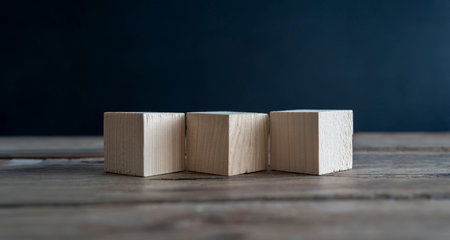 Blank wooden cube blocks on the table. Three pieces are placed side by side, six sides can be seen.