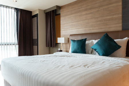 Hotel room with king size bed and floor windows. Design bedroom contemporary style room with wooden furniture white interiors and textiles. the bedroom has a large window bright colors.の写真素材