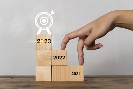 Get ready for success in 2023, hand finger walk on stacked wooden block like stairs. rises on the...