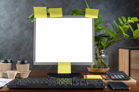 Computer monitor with white blank screen on the business desk with calculator, keyboard at home office over dark wall background, Photo of equipment contemporary workspaceの写真素材