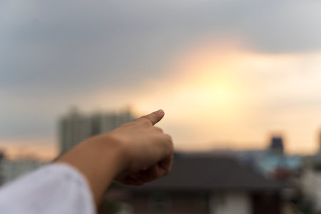 Counting with finger, finger concept, hand work. Close-up female hand with index finger up on a background of golden sky with clouds, copy space.の写真素材