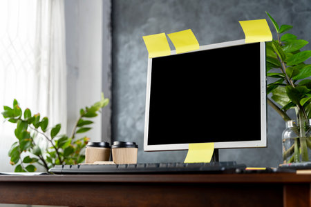 Contemporary office and computer monitor with blank screen on the desk technology and business concept dark loft backgroundの写真素材