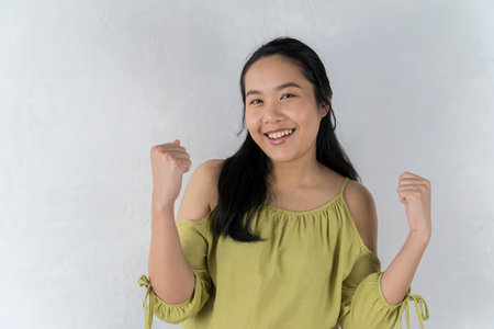 Great Offer. great deals An Asian girl in a cheerful green shirt points to a handful of invisible objects. pose over a gray backgroundの写真素材