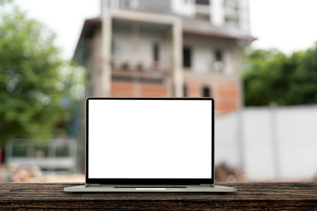 Construction house and building. Repair work. laptop screen blank white. Blur the background of the ongoing construction of a house. Architect concept.の写真素材