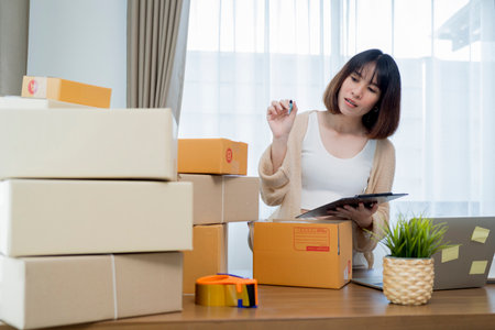 Startup small business owner working at home, women sealing cardboard box with adhesive tape, Online shopping business, ecommerce and delivery to customer conceptの写真素材