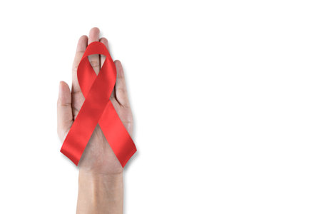 World aids day and national HIV AIDS and ageing awareness month with red ribbon on helping handの写真素材