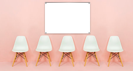 White chair on orange background. The picture frame is at the back and has space for advertising...
