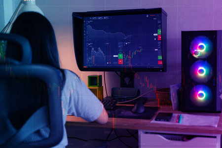 Back view of female trader looking at monitor with stock exchange graph or chart.Centennial young person seen from behind buying and selling cryptocurrency in her smartphoneの写真素材