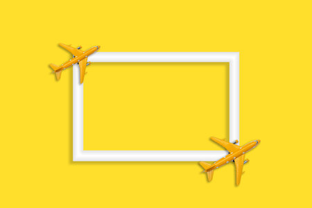 Top view of yellow airplane model and white blank frame on yellow background.Can put advertising text.の写真素材