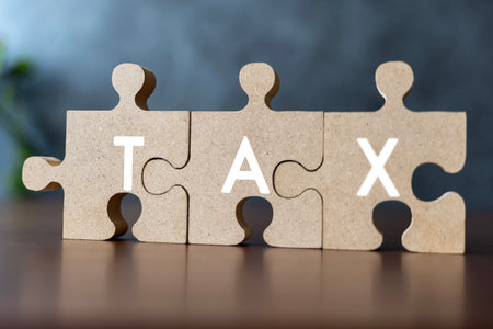 Taxes concept with wooden puzzle on a desk. Jigsaw puzzle as the task of putting together a complicated tax return each year. This is an illustration isolated on the background.の写真素材