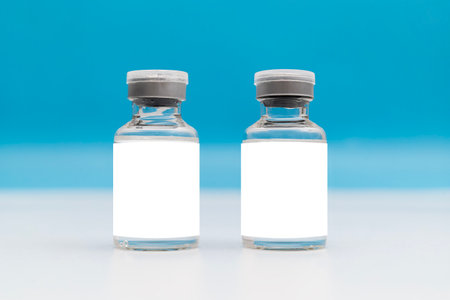 Glass ampoule of vaccine with blank label, isolated on a white background. Vial blue bottle for...