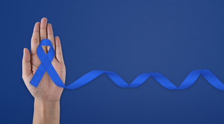 Man holding dark Blue Ribbon for supporting people living and illness. Healthcare, hope and World cancer day concept. March Colorectal Cancer Awareness month.の写真素材