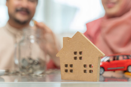 Muslim couple with jar of coins. Woman hand putting money in the glass jar labeled held by a man, save and investment money for prepare. Saving money concept to buy house, car, life insuranceの写真素材