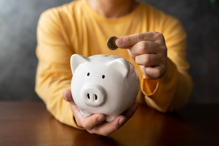 Piggy bank savings, investment and hand with money, coin or silver investing in future wealth, financial growth or economy wealth. Accounting man saving change or cash for profit, finance and budgetの写真素材
