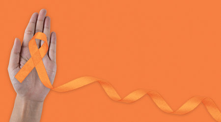 February awareness month. Hand holding Orange Ribbon for Leukemia, Kidney cancer day, world Multiple Sclerosis, CRPS, Self Injury Awareness month. Healthcare and word cancer day conceptの写真素材