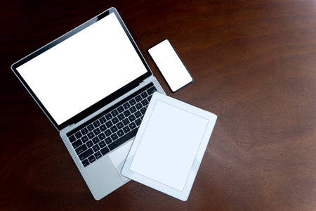 Laptops, tablets and smartphones with blank screens on table, devices are highly used in communication technology these days. Flat top view with copy space.の写真素材