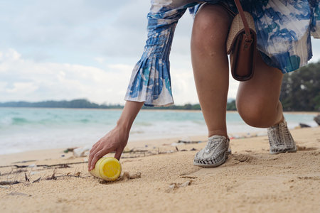 Volunteer woman picking plastic bottle into trash plastic bag black for cleaning the beach, female...