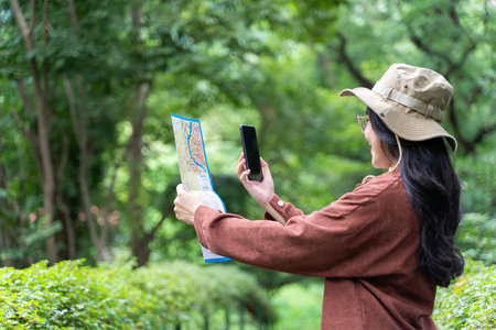 Woman hands with a smartphone and map in the forest background, isolate screen. Happy young woman...