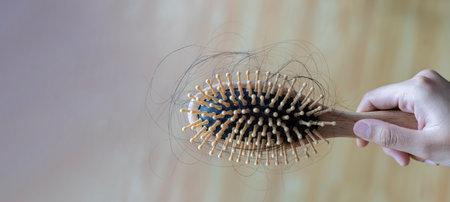 Serious, worried asian young woman, girl holding comb, show her hairbrush with long loss hair problem after brushing, hair fall out problem. Health care, beauty with copy space.の写真素材