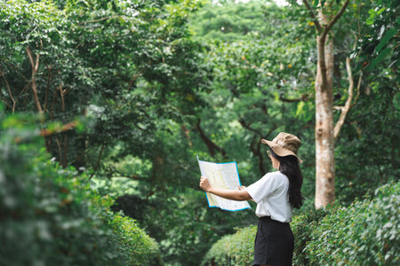 Traveling Happy Asian woman walking on path the tropical forest looking map in green rainforests. Summer holiday and vacation trip , Survival travel, lifestyle conceptの写真素材